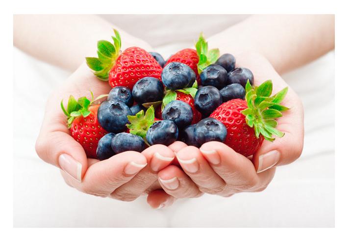 Nutrition and a healthy diet for weight loss: hands holding blueberries and strawberries